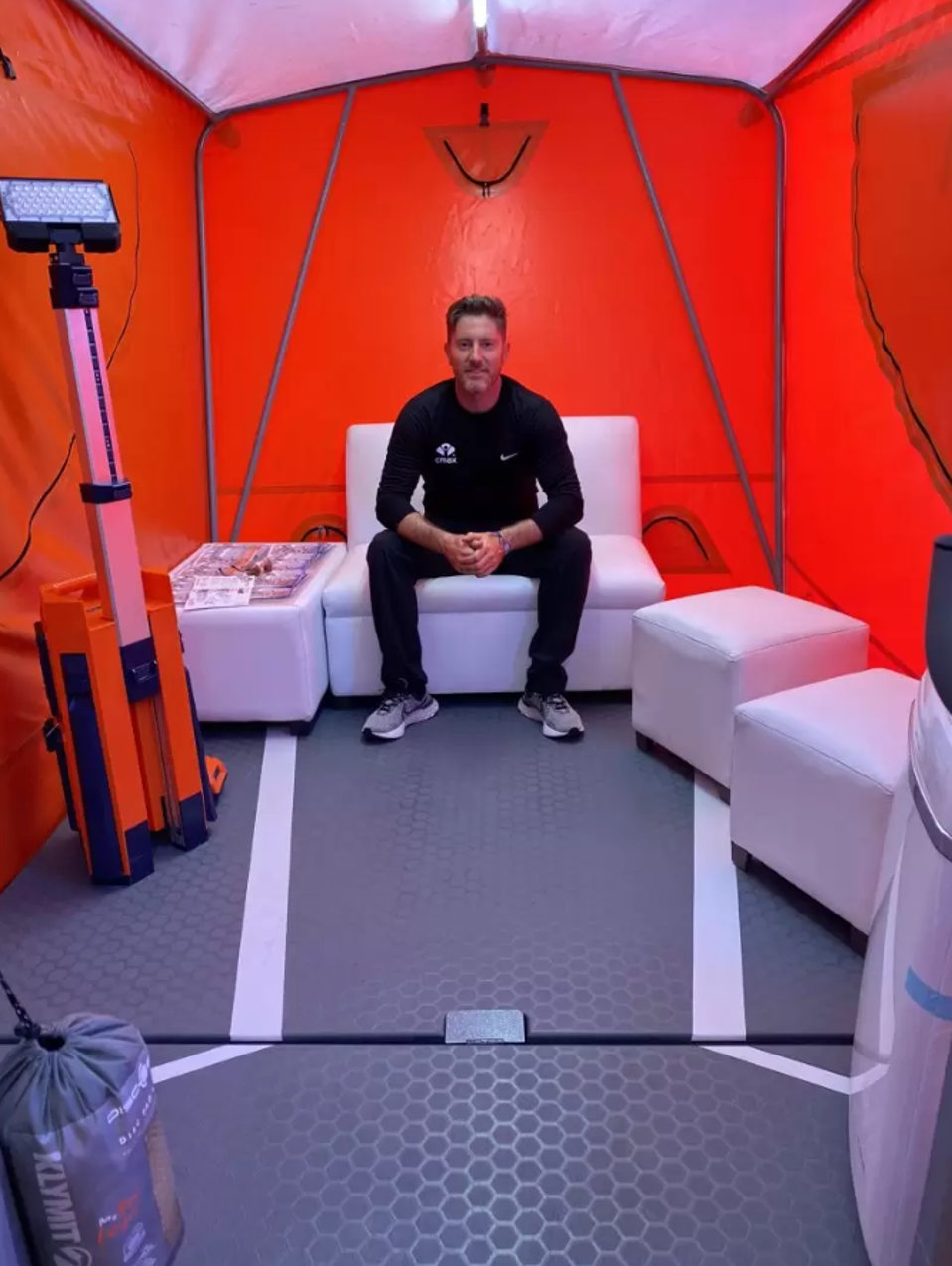 Nicolás García Mayor sits inside an orange tent on a white chair.