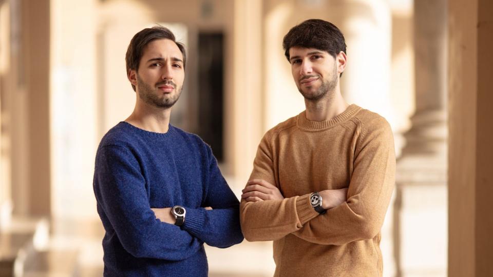 Alberto and Alessandro Morelli wear solid sweaters and cross their arms.