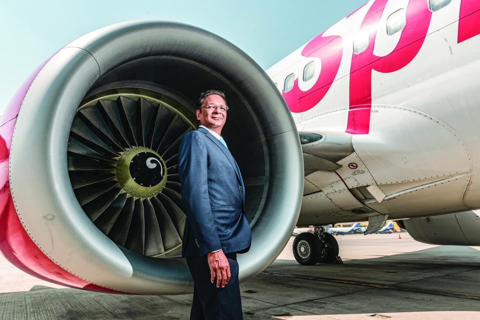 Ajay Singh stands beside a airplane.