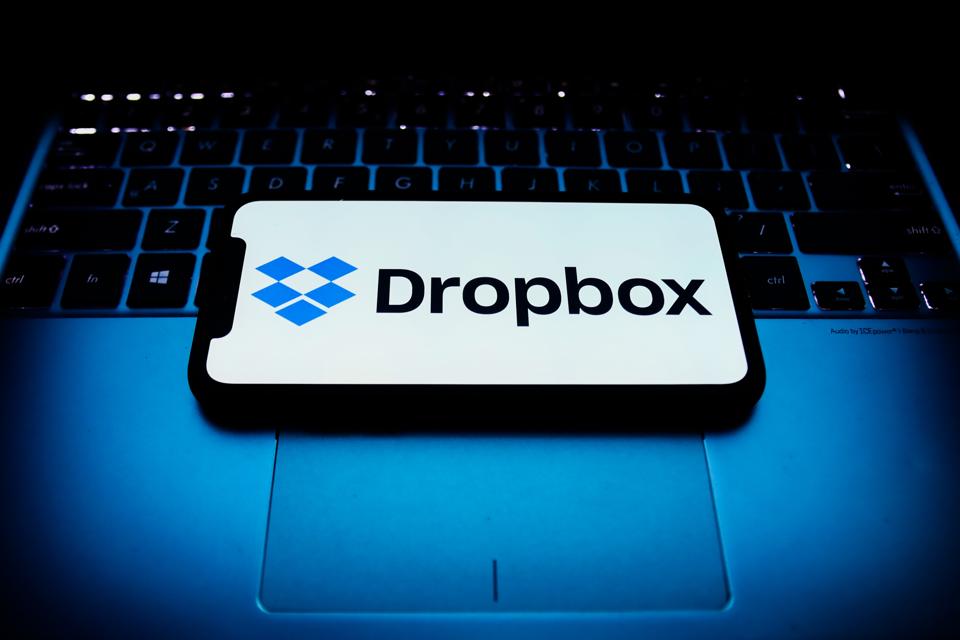 Dropbox logo displayed on a phone screen and a laptop keyboard.