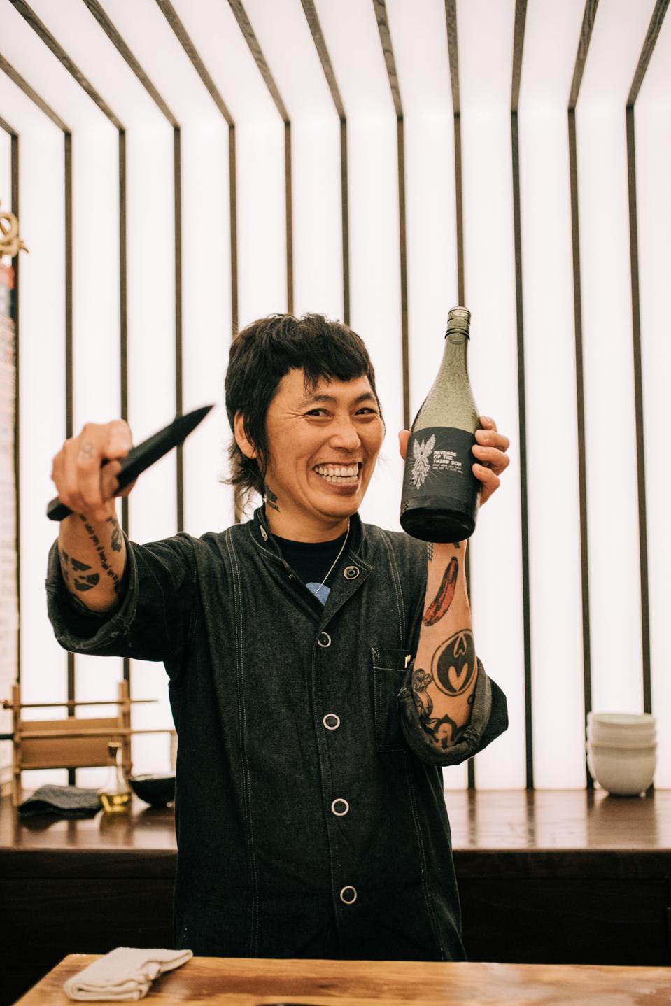 Chef Yoshi Okain holding a knife and bottle