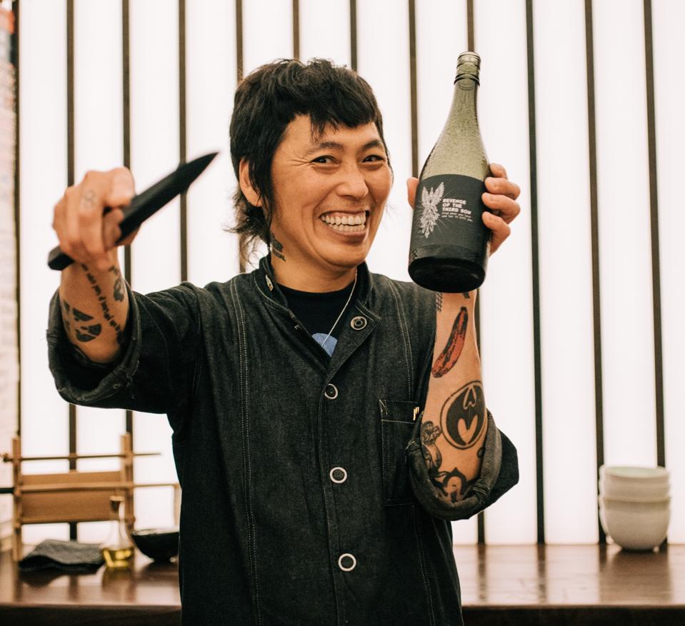 Chef Yoshi Okain holding a knife and bottle