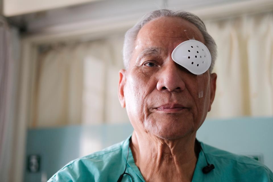 patient covering eye with protective shield after eyes cataract surgery in hospital