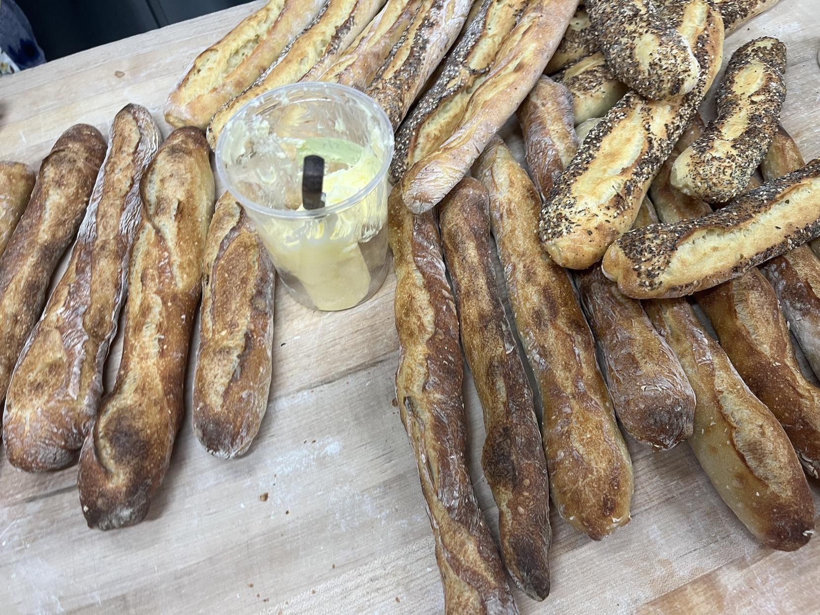 A collection of baguettes sits on a table.
