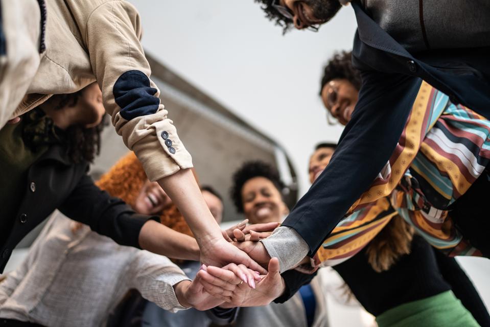 Group of diverse individuals stacking hands in a circle to show solidarity.