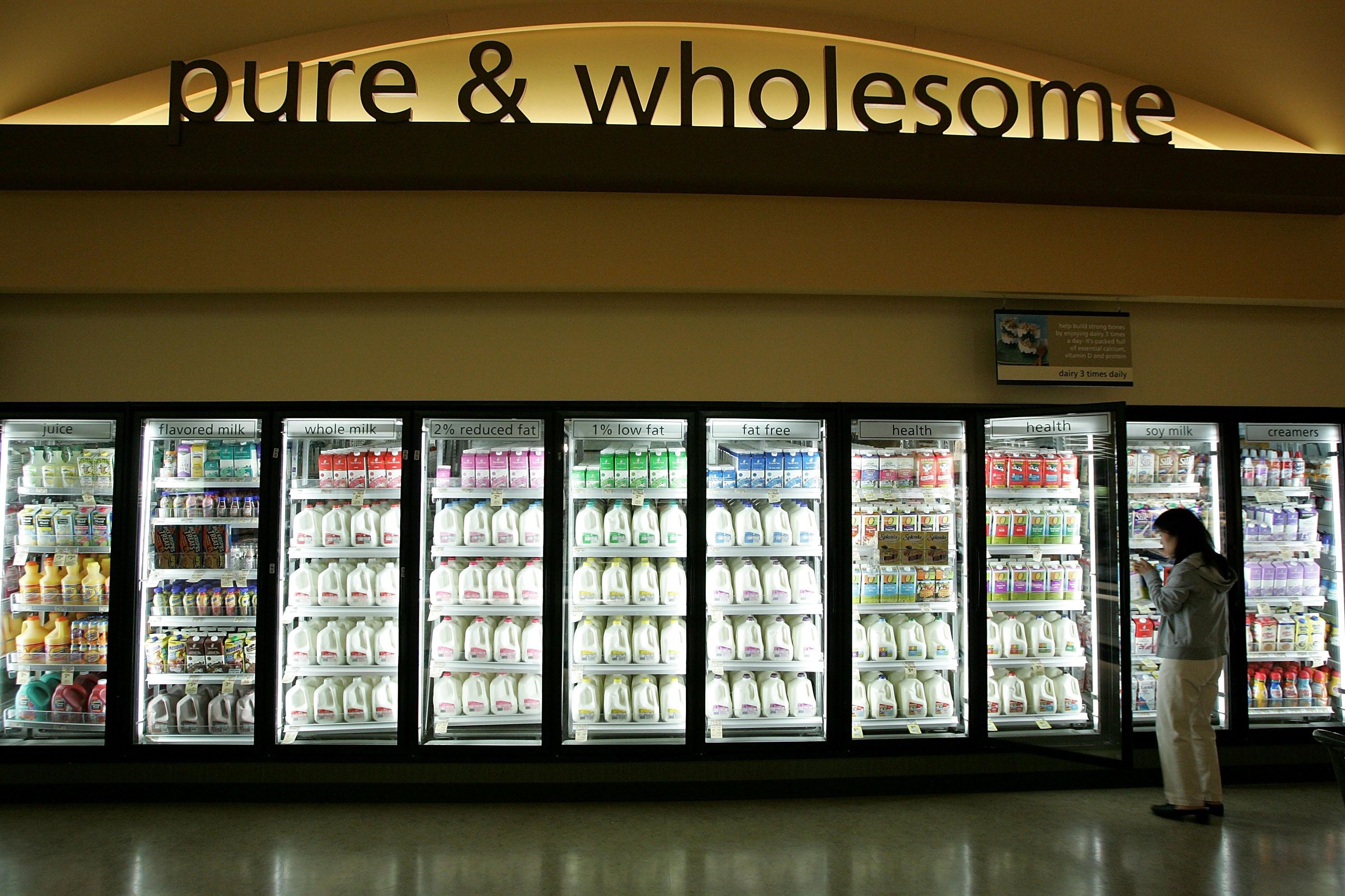 A grocery store dairy aisle displays milk in cold cases.