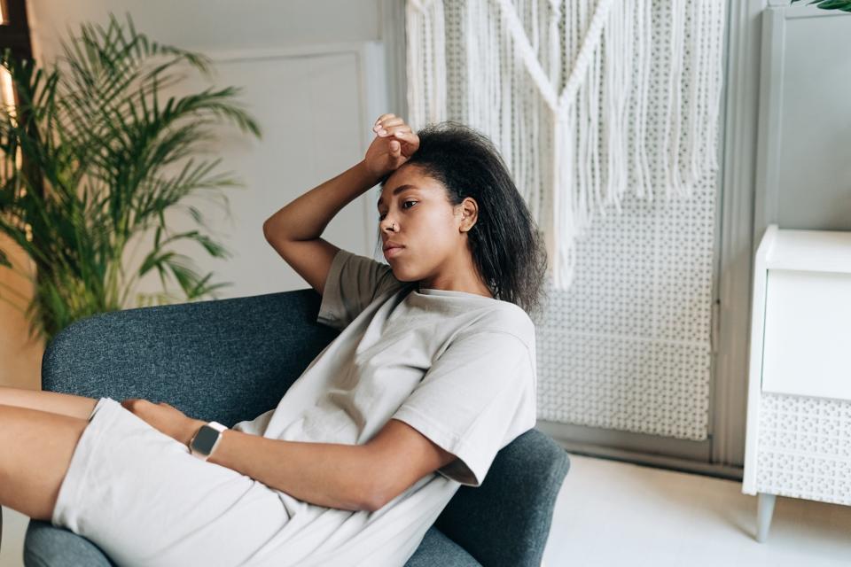 Sad depressed woman suffering from insomnia, she is sitting in bed and touching her forehead, sleep disorder and stress concept