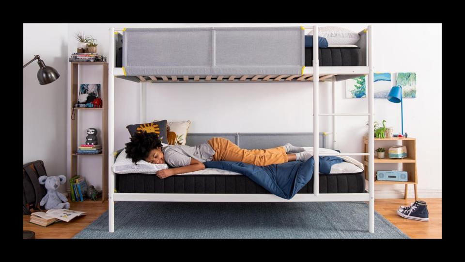 A boy lying down on the Nest Puffin mattress on a white bunk bed frame.