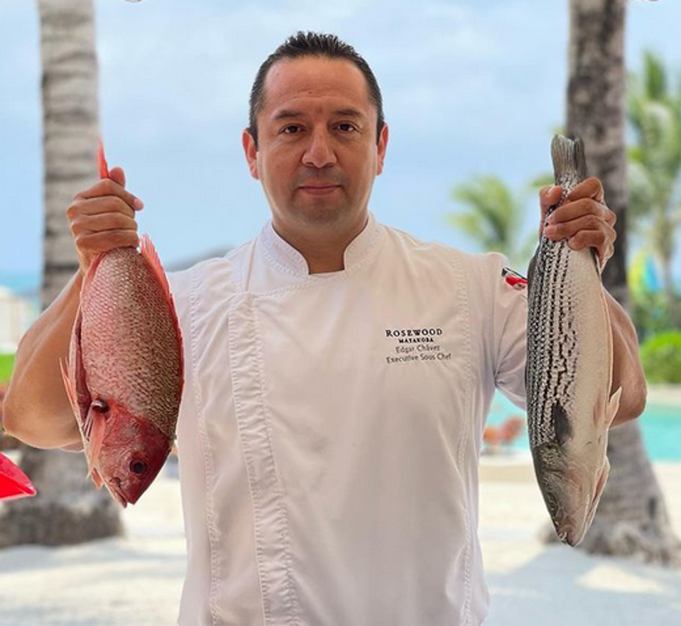 Edgar Chávez holding a fresh fish in each hand