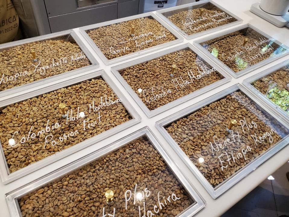 bins with green coffee beans under glass