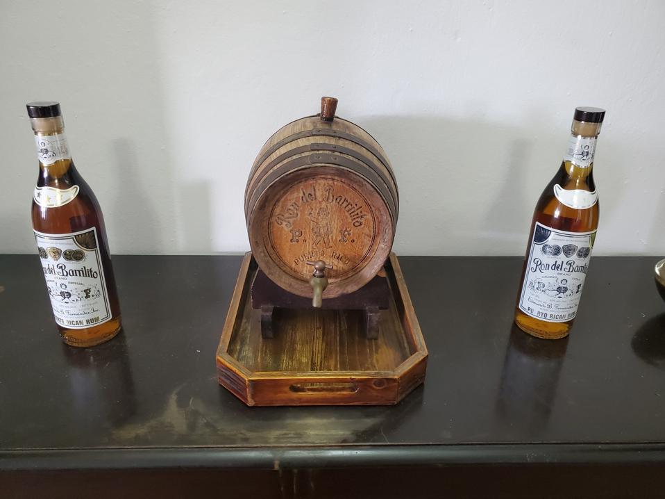 a small wooden barrel and two rum bottles on a tabletop