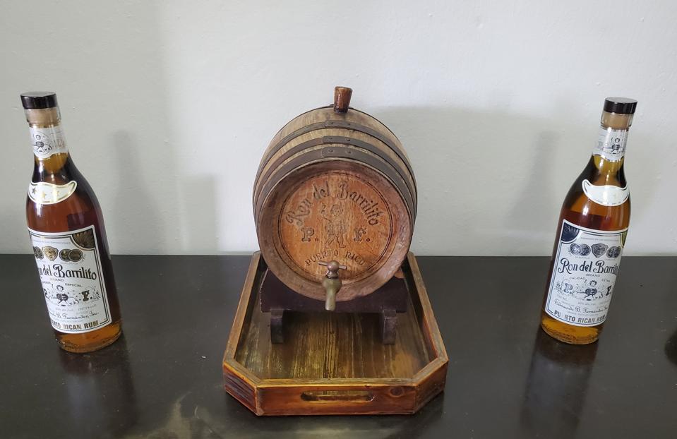 a small wooden barrel and two rum bottles on a tabletop