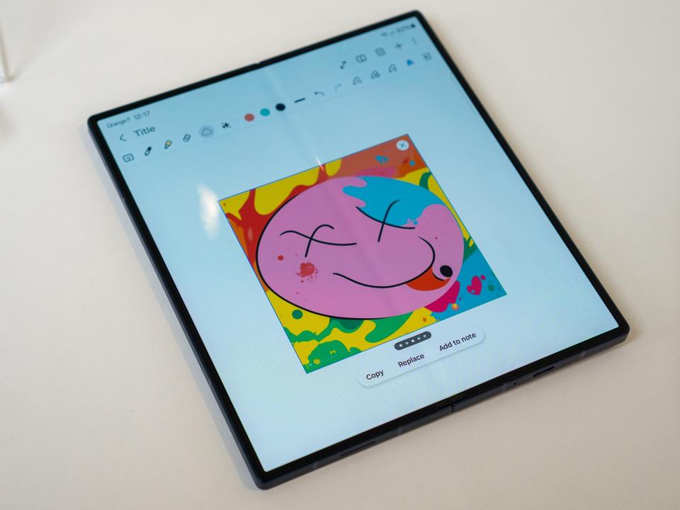 A Samsung Galaxy Z Fold 6 with an AI image of a smiley face on a white table
