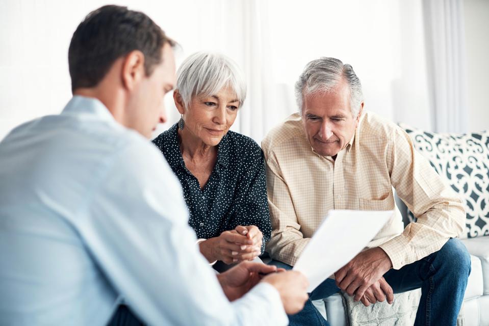 Old man and woman discussing with younger male financial advisor