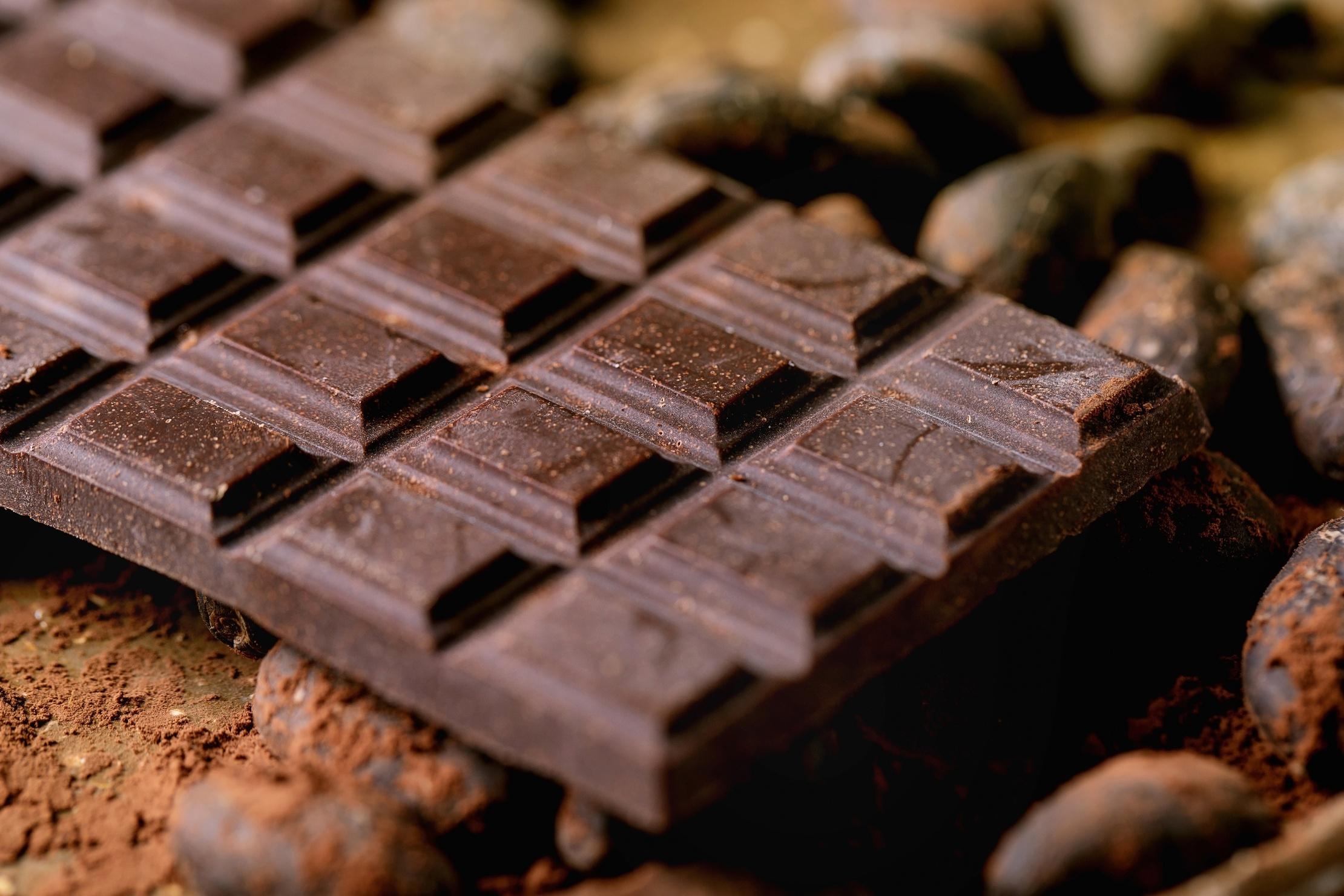 Dark chocolate bar with cocoa beans, cocoa powder. Food background. Close up.
