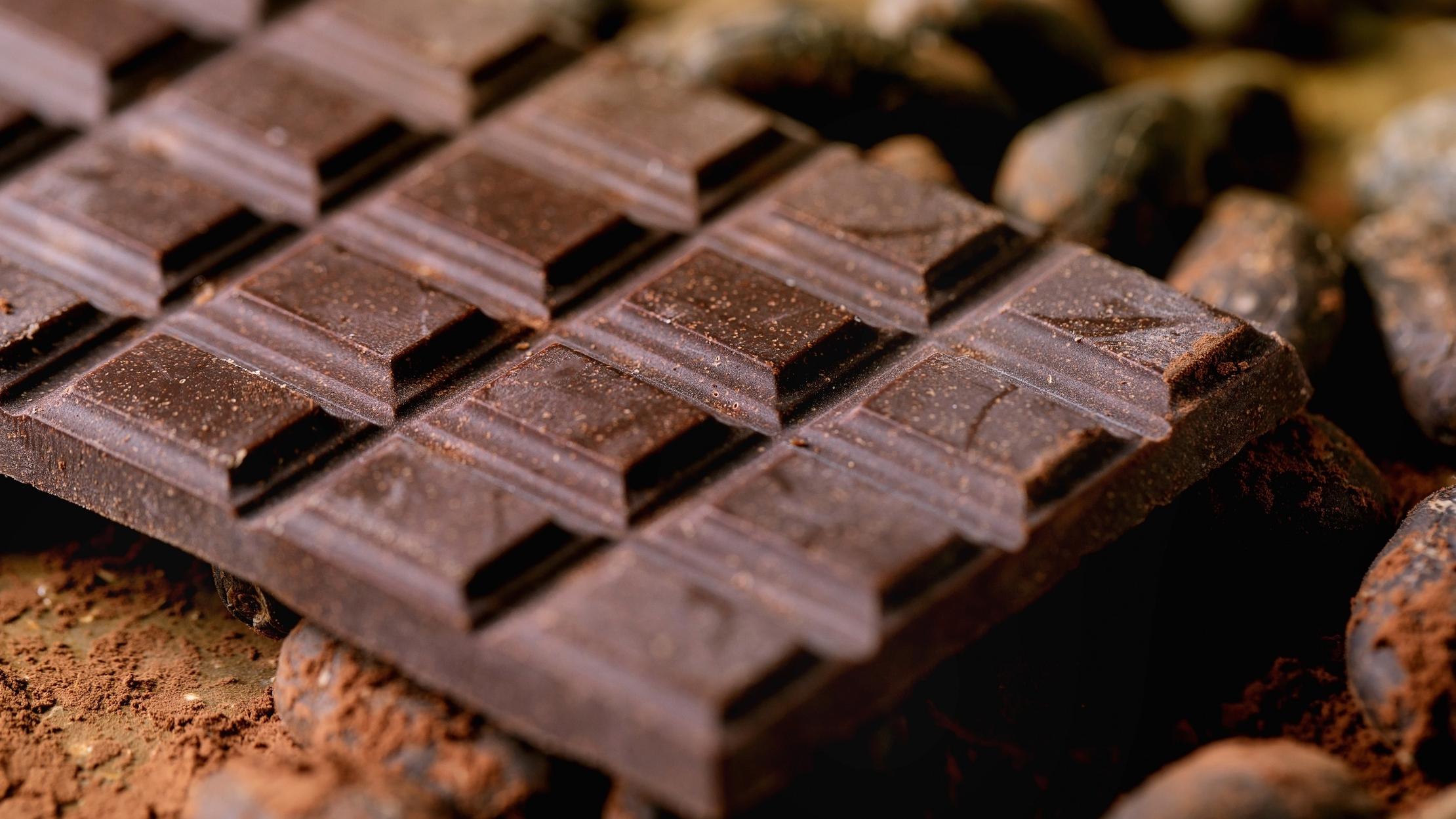 Dark chocolate bar with cocoa beans, cocoa powder. Food background. Close up.