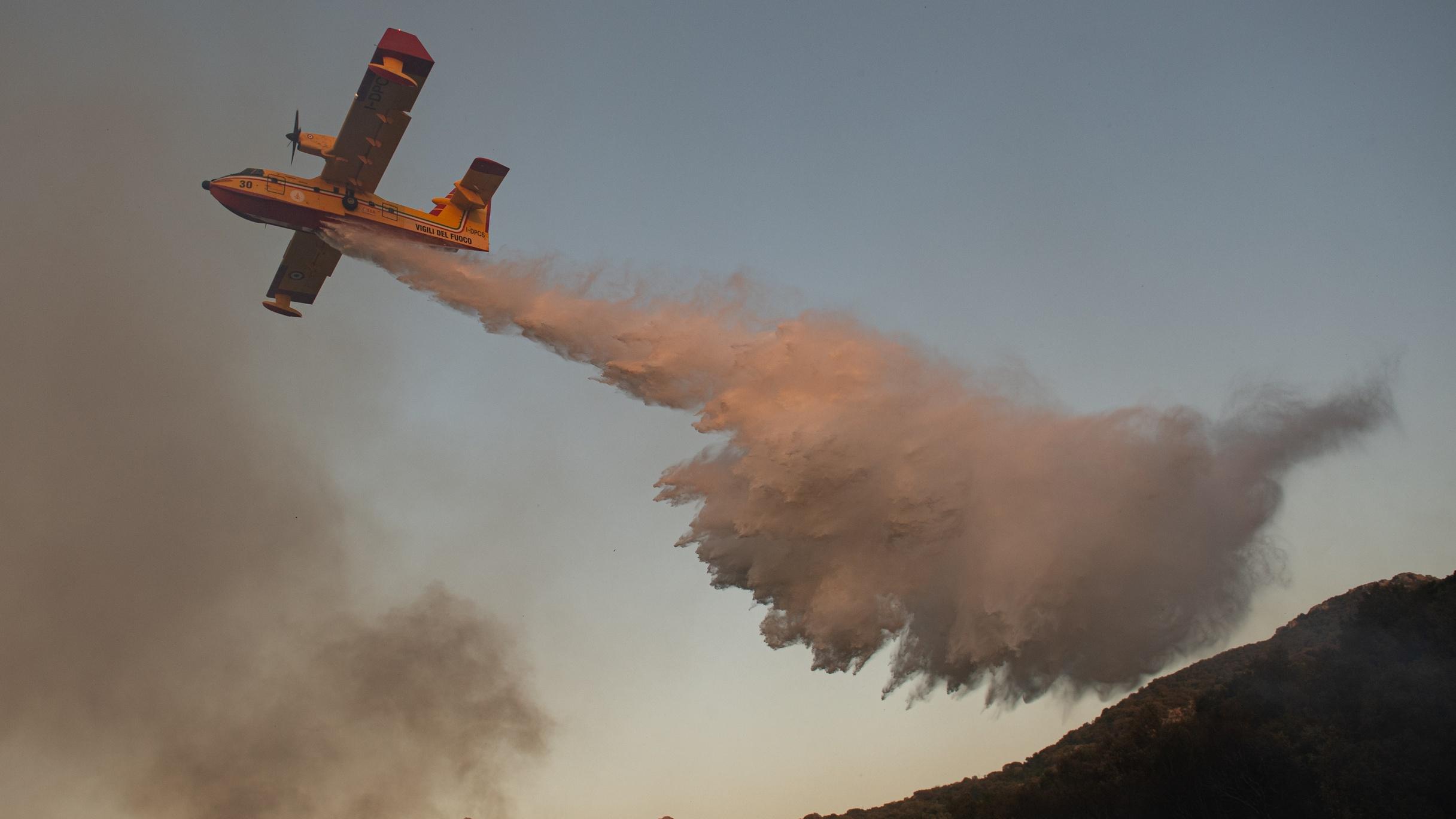 An airplane drops water on a wildfire in Italy.