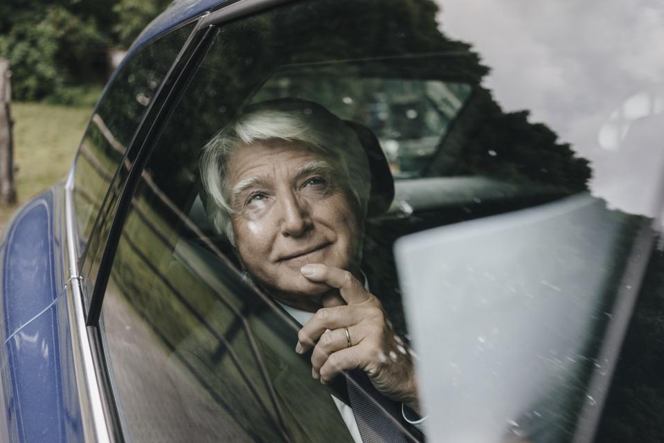 Portrait of senior businessman looking through car window