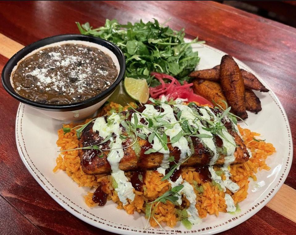 Jollof rice with salmon, black beans, fried plantains, arugula and pickled onions