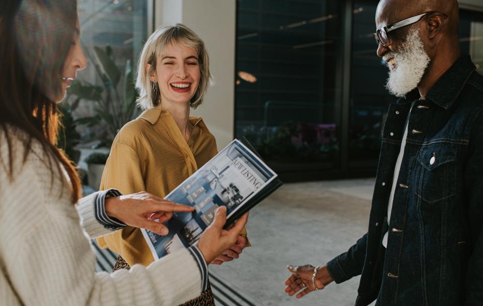 A woman and a man listen to an estate agent who briefs them on a property