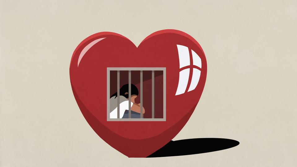 Sad woman sitting behind bars in prison of heart