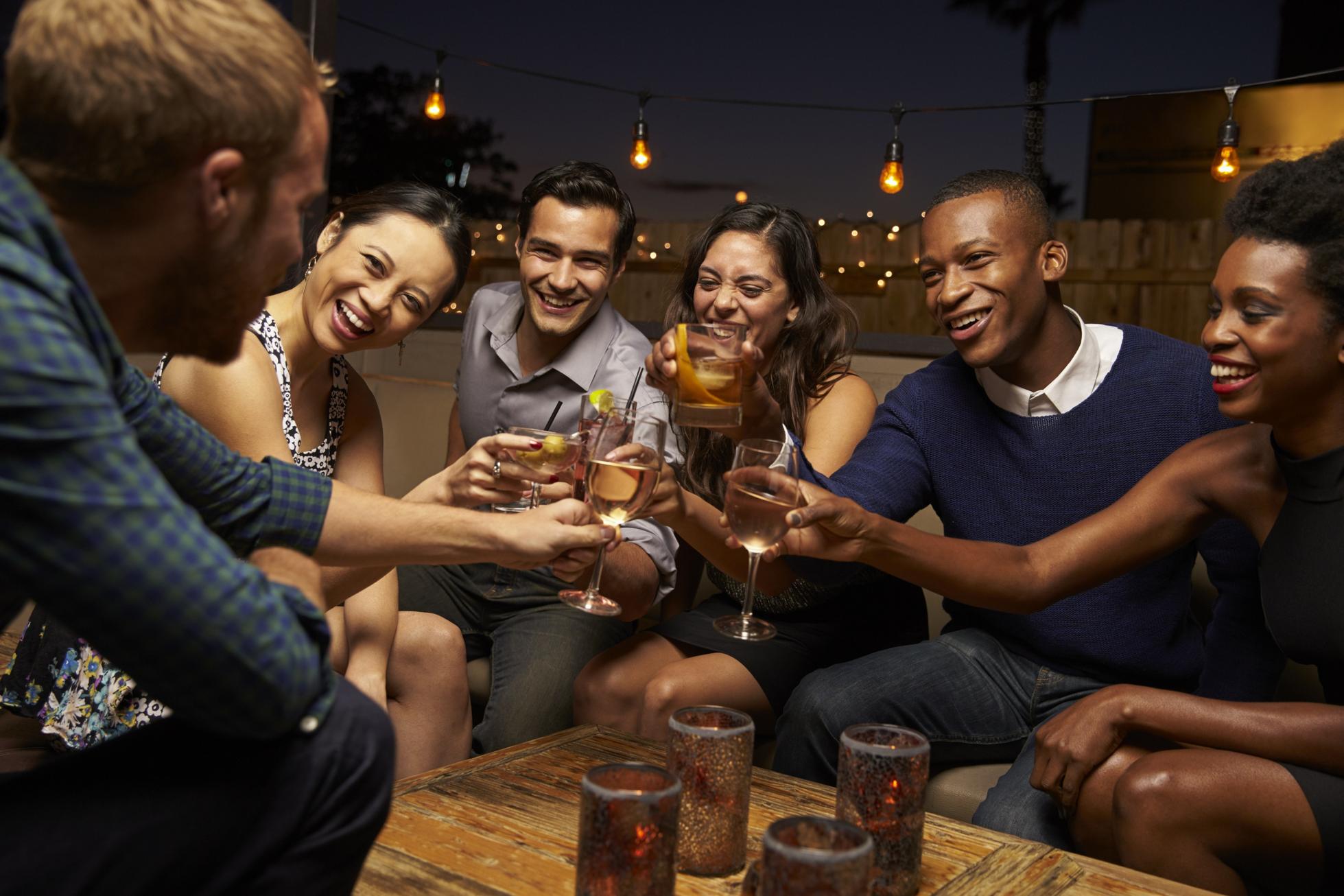 Group Of Friends Enjoying Night Out At Rooftop Bar