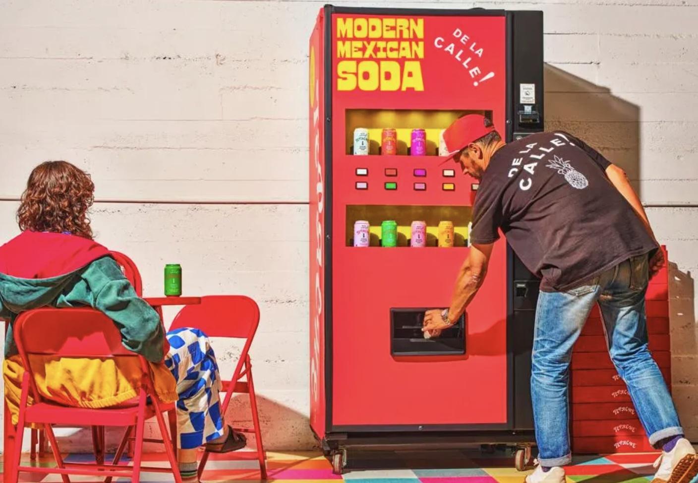 A man reaches into a De La Calle vending machine that offers Modern Mexican Soda.