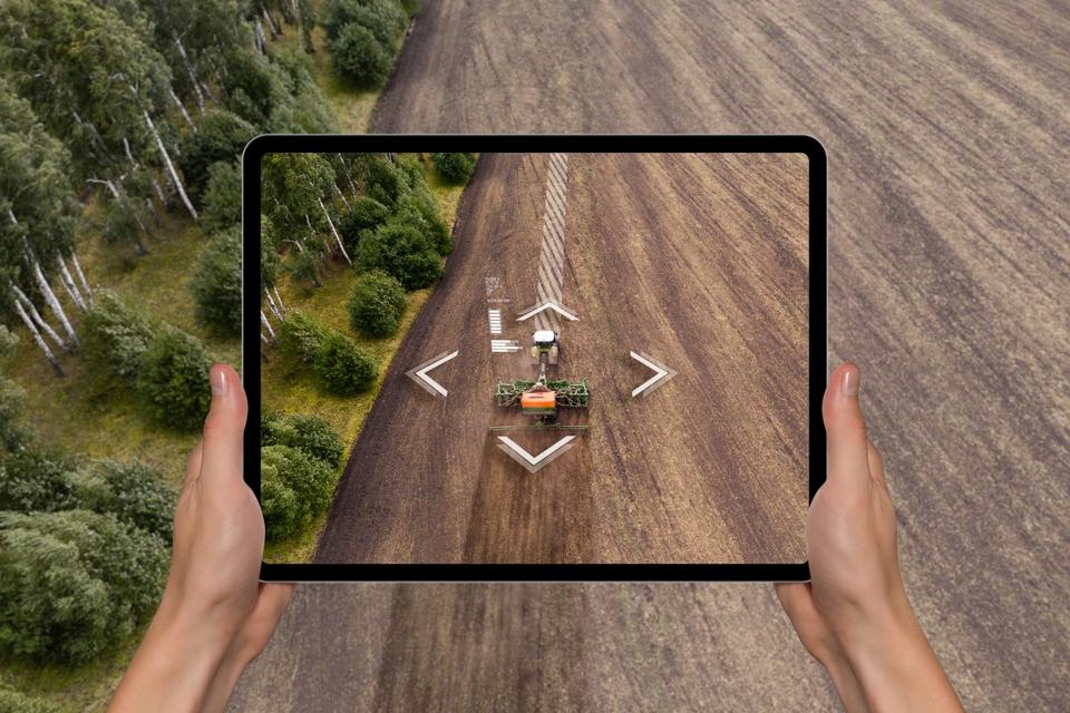 A farmer with digital tablet controls an autonomous tractor