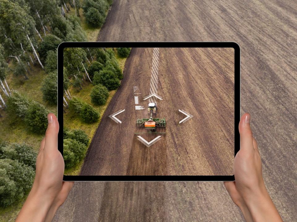 A farmer with digital tablet controls an autonomous tractor