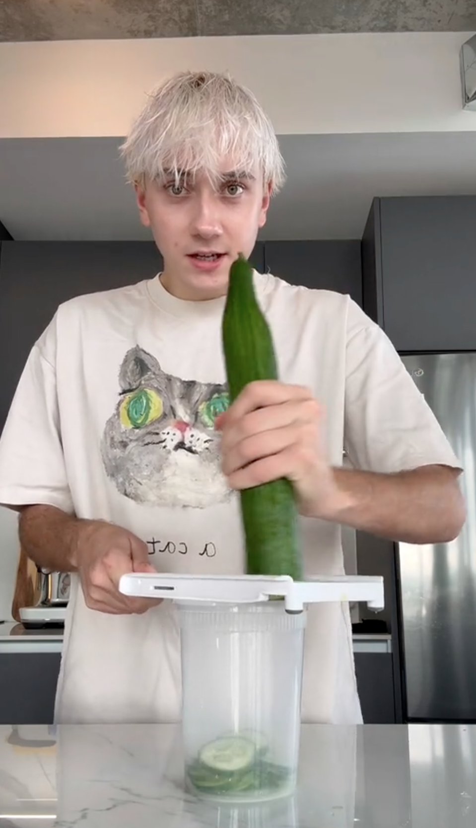 Logan Moffitt slicing a cucumber with a mandolin