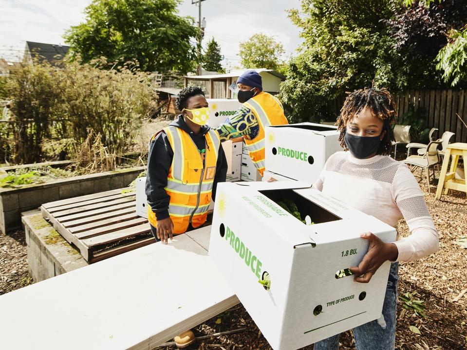 Woman wearing protective face mask picking up CSA box at community farm