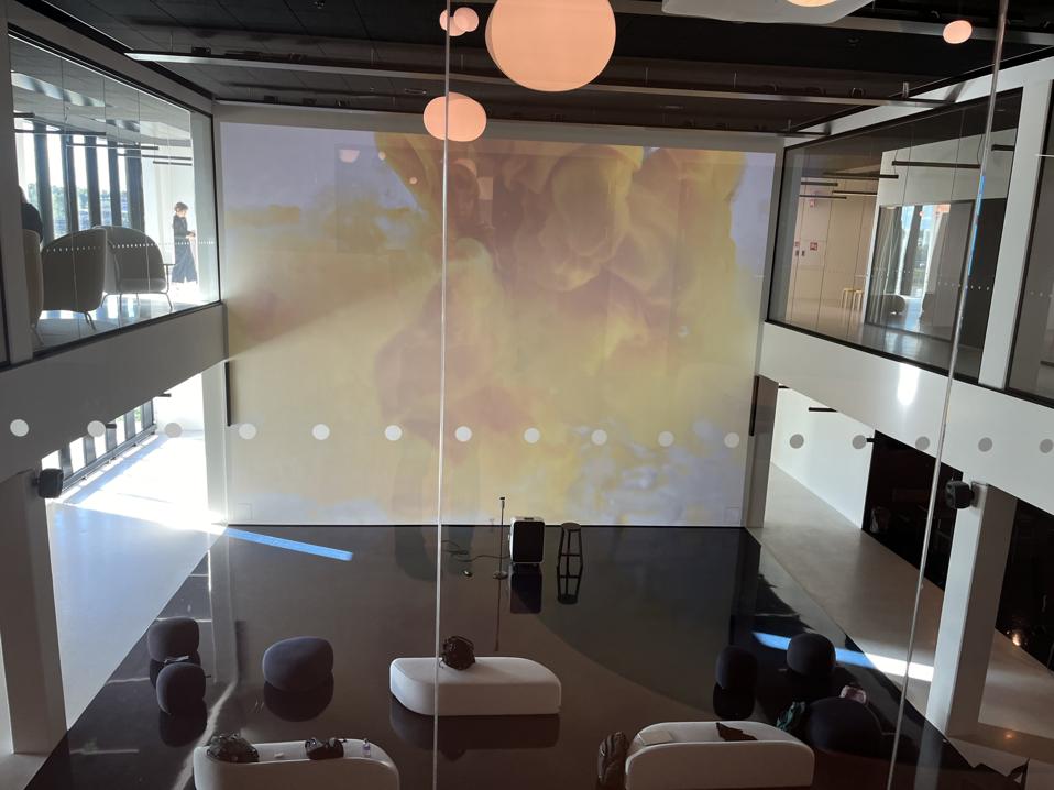 A high-ceilinged room with an image of yellow powder projected on the wall