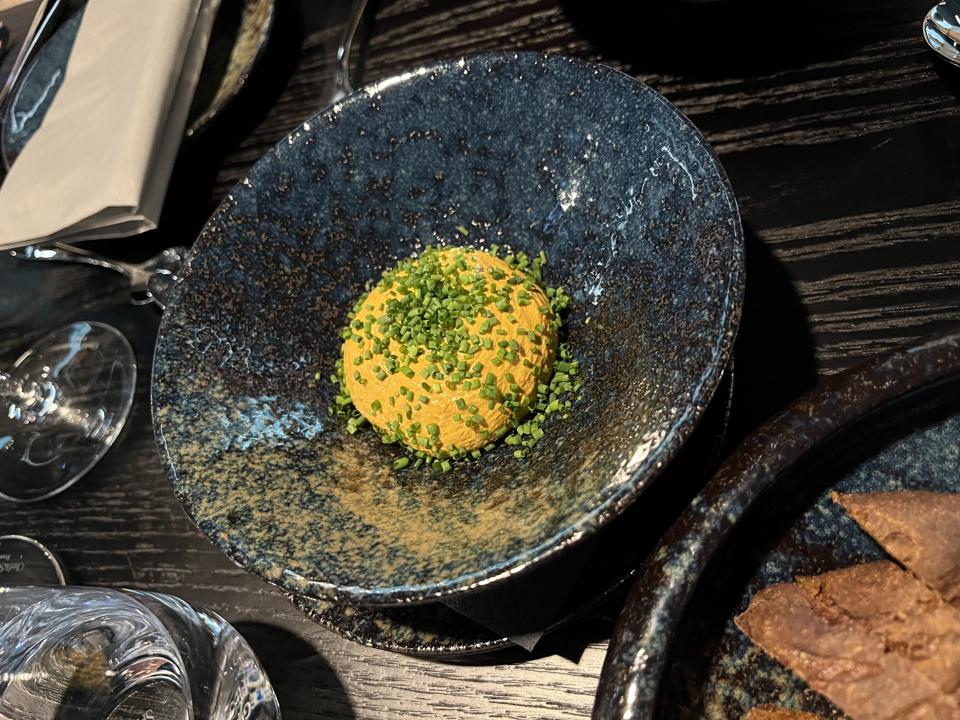 Black bowl with creamy orange mound, studded with flecks of green
