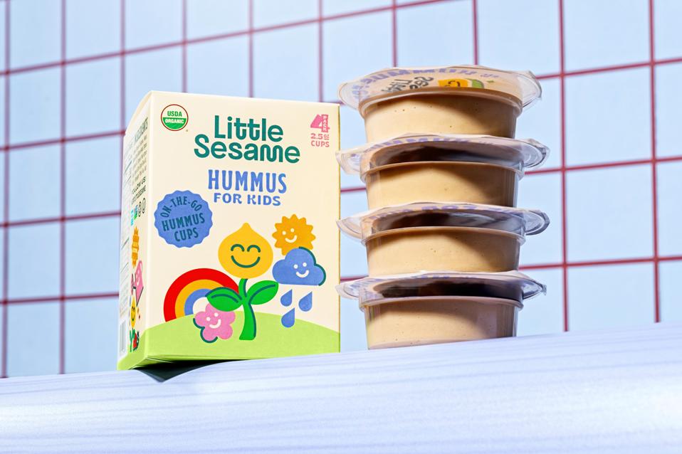 Four stacked cups of Little sesame hummus and box