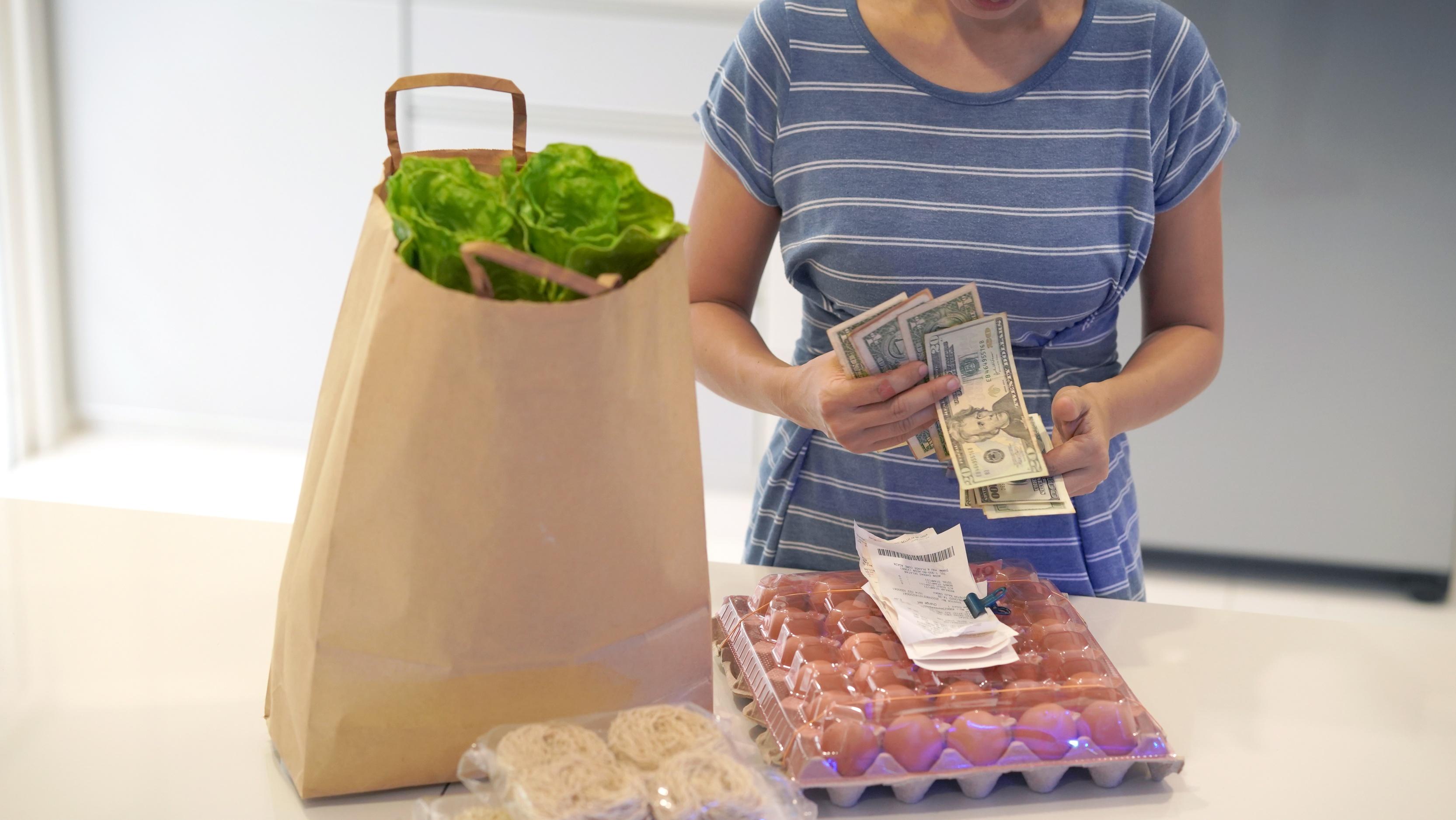 woman calculative buying grocery due to price increase inflation