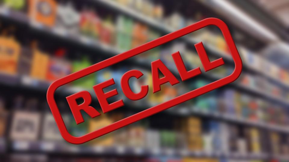 Blurry interior of a grocery store aisle behind large red Recall text