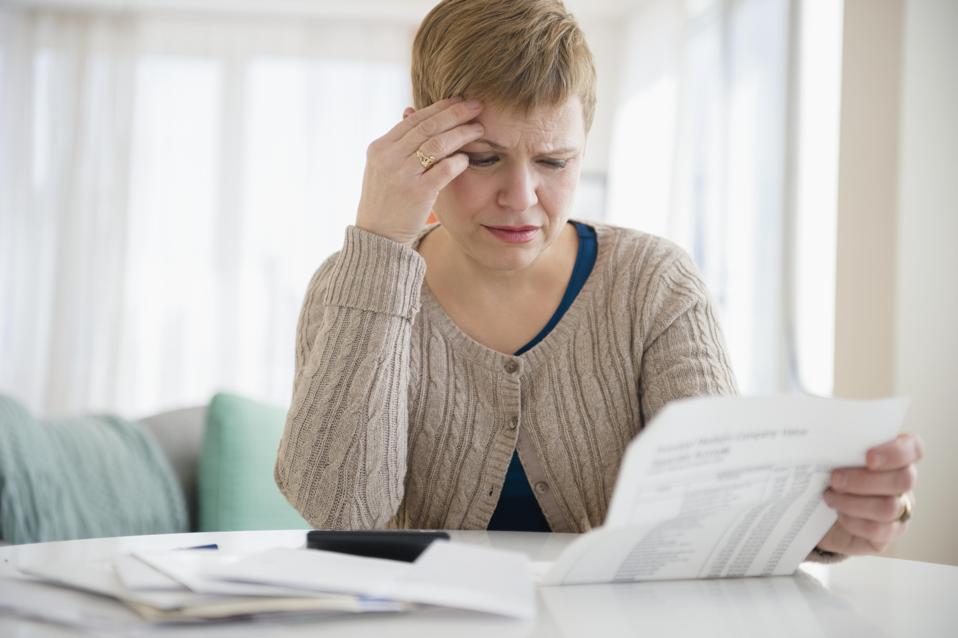 Person looking at documents while holding head with hand