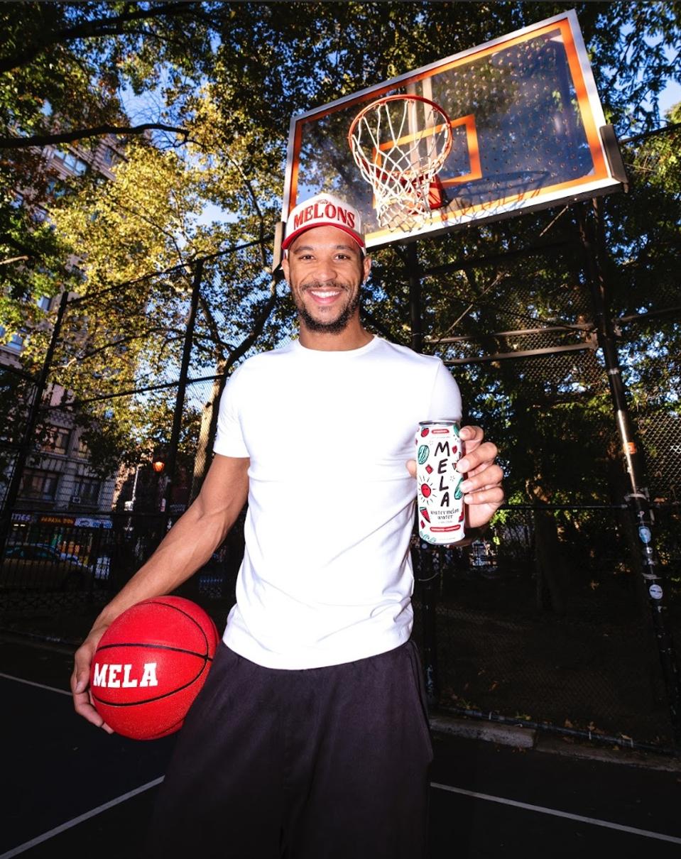 Josh Hart on a basketball court holding Mela watermelon water