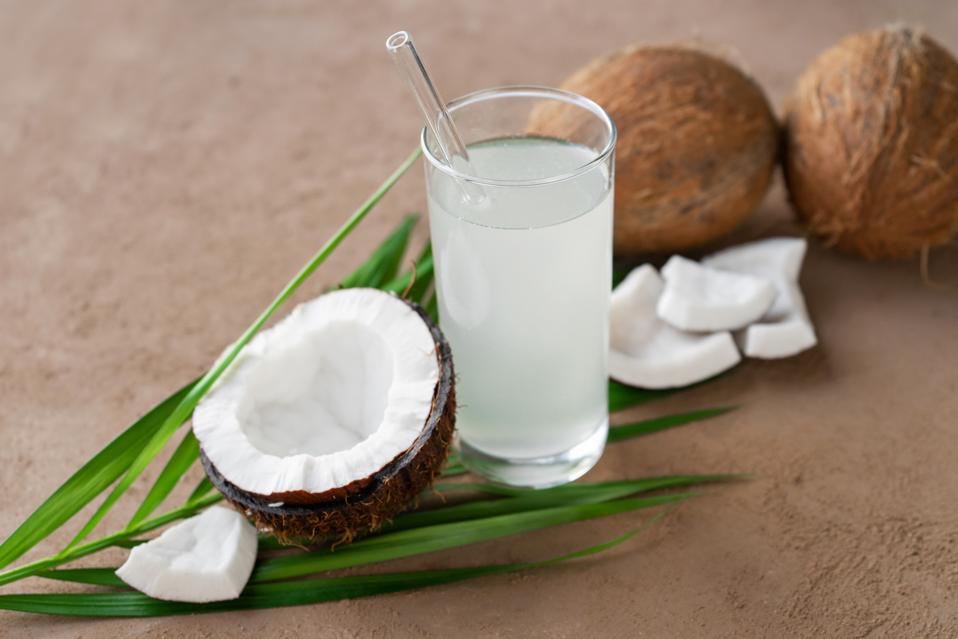 image of glass of coconut water, coconuts and palm leaf