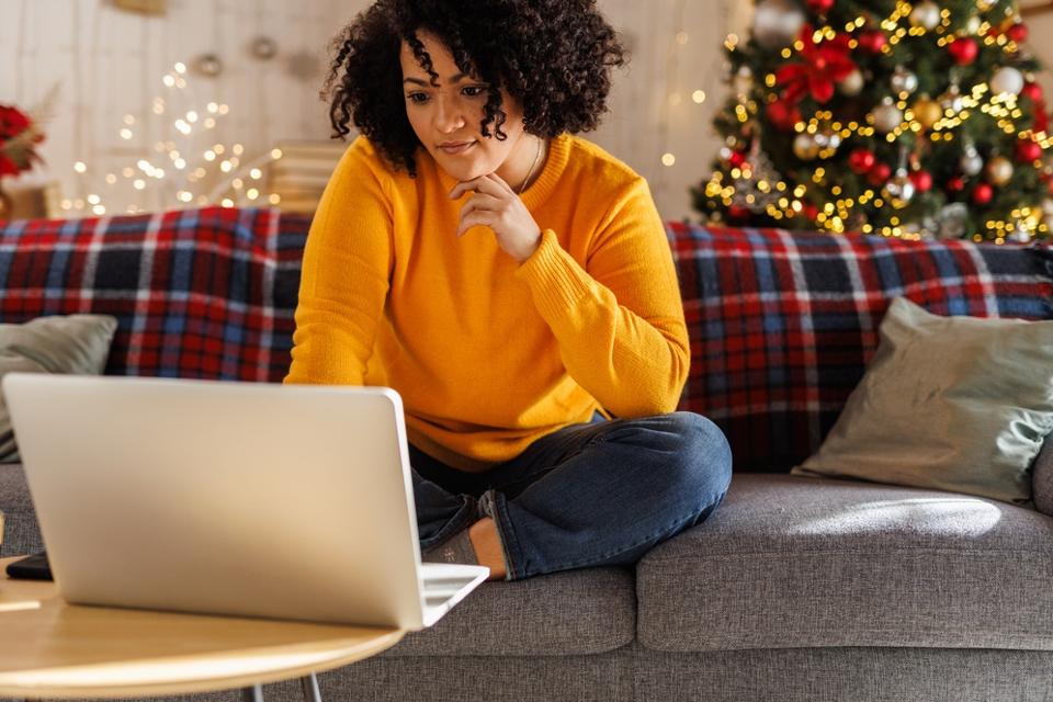 Young woman lounging on the sofa, using laptop