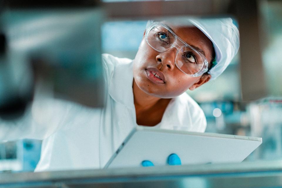 Female engineer in a factory in professional uniform using digital tablet