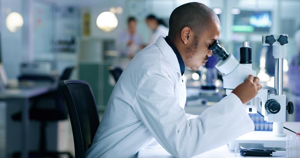 Research scientist analyzing a sample, looking into a microscope, conducting an experiment.