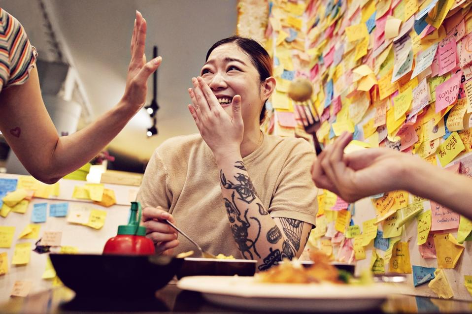 Happy woman with tattoo having food at cafe