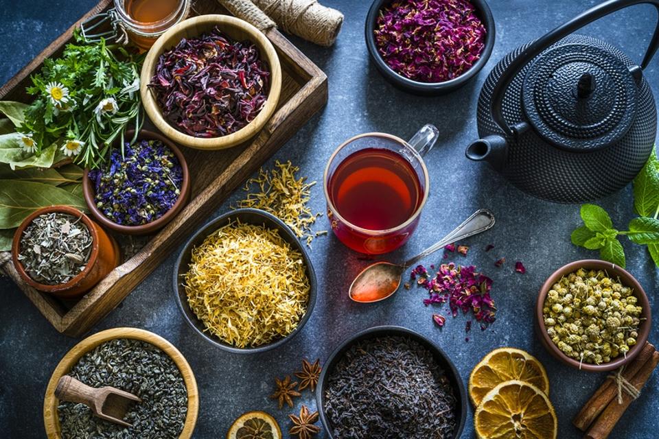 Cup of tea with multi colored dried tea leaves and flowers on blue table