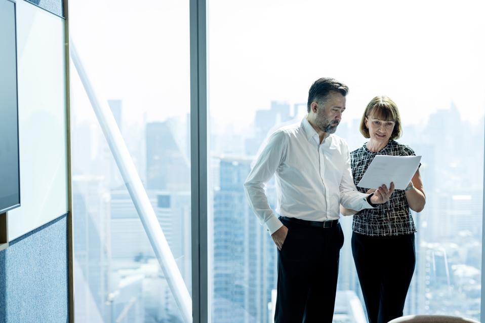 Business Growth Through Acquisition, Mergers and Partnerships. Senior businesswoman with her business discussion on a business agreement during a board meeting in a business office.