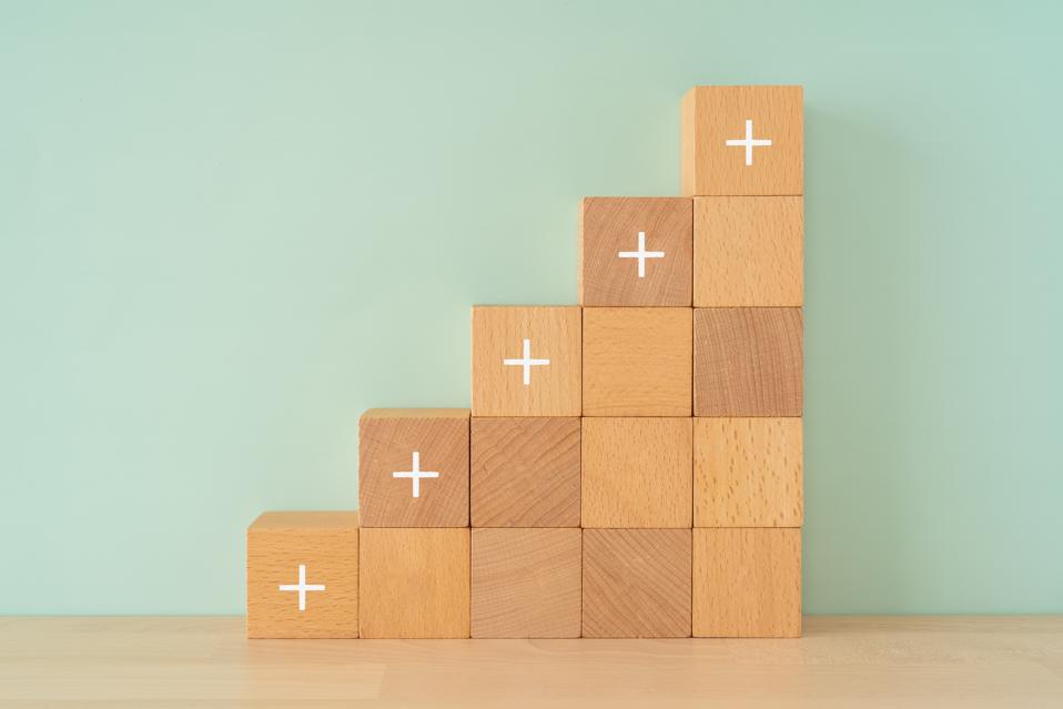 Wooden blocks with plus text of concept.
