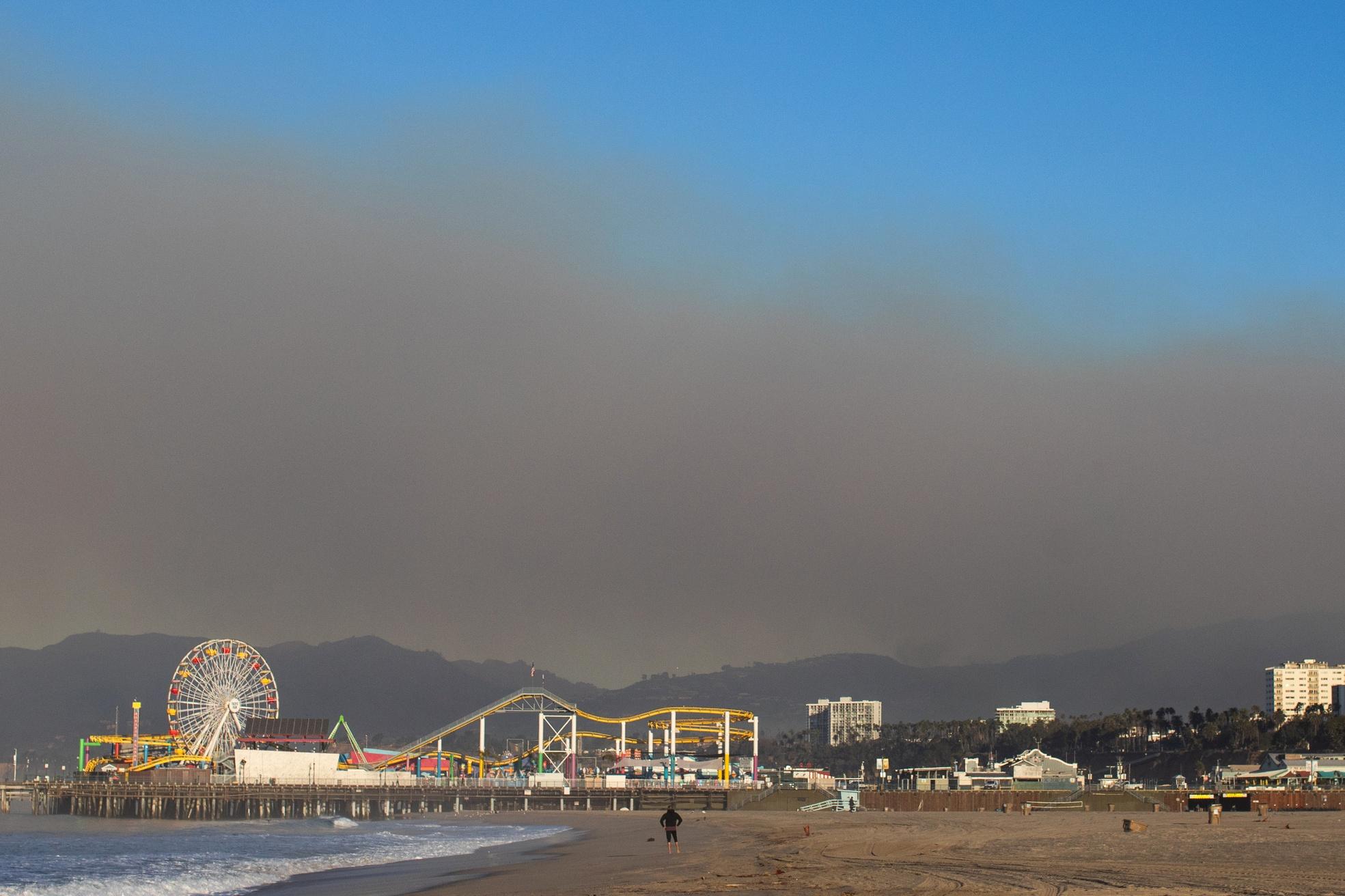 A view of the Santa Monica Pier in California with wildfire smoke hovering above it.