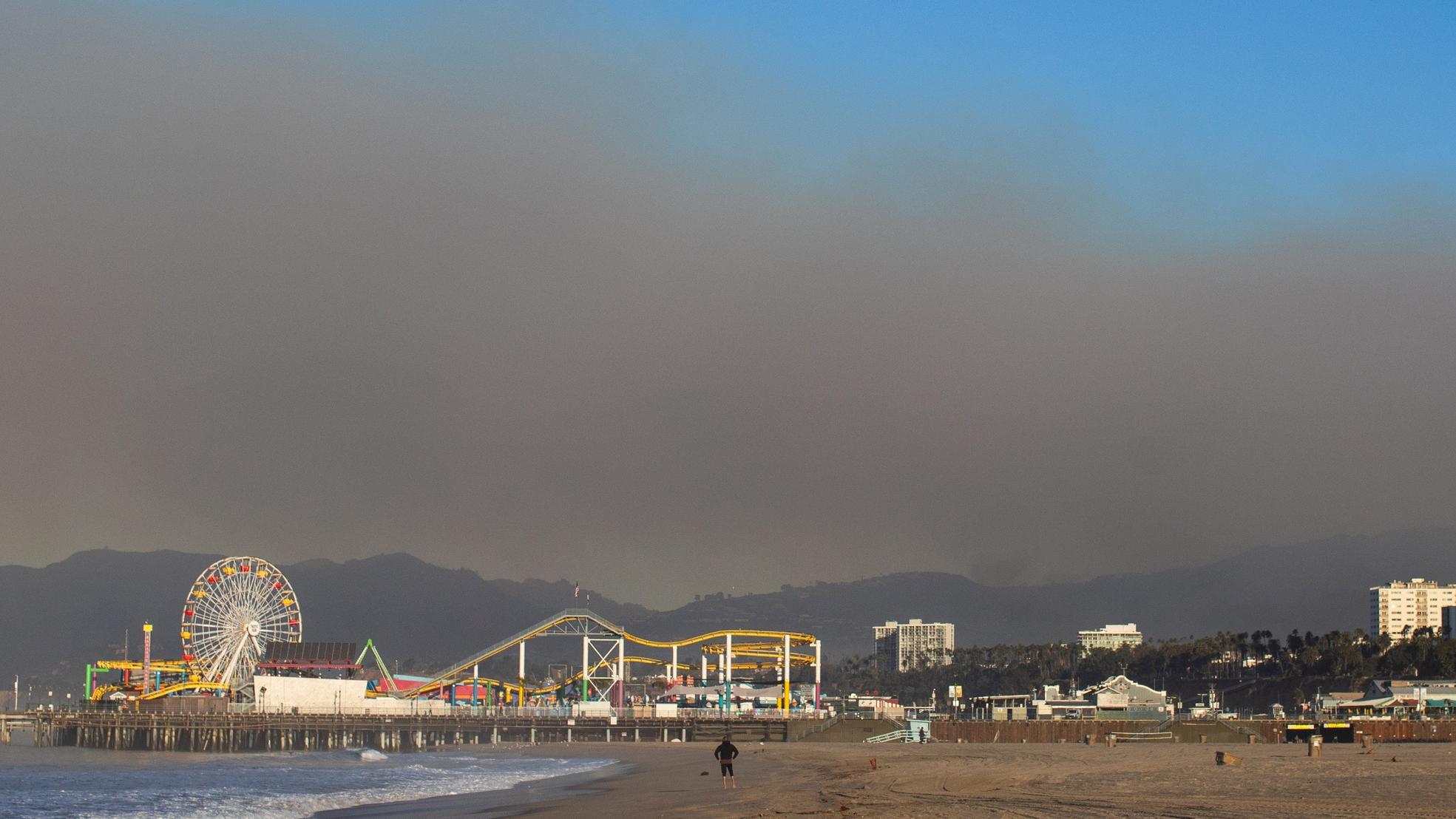 A view of the Santa Monica Pier in California with wildfire smoke hovering above it.