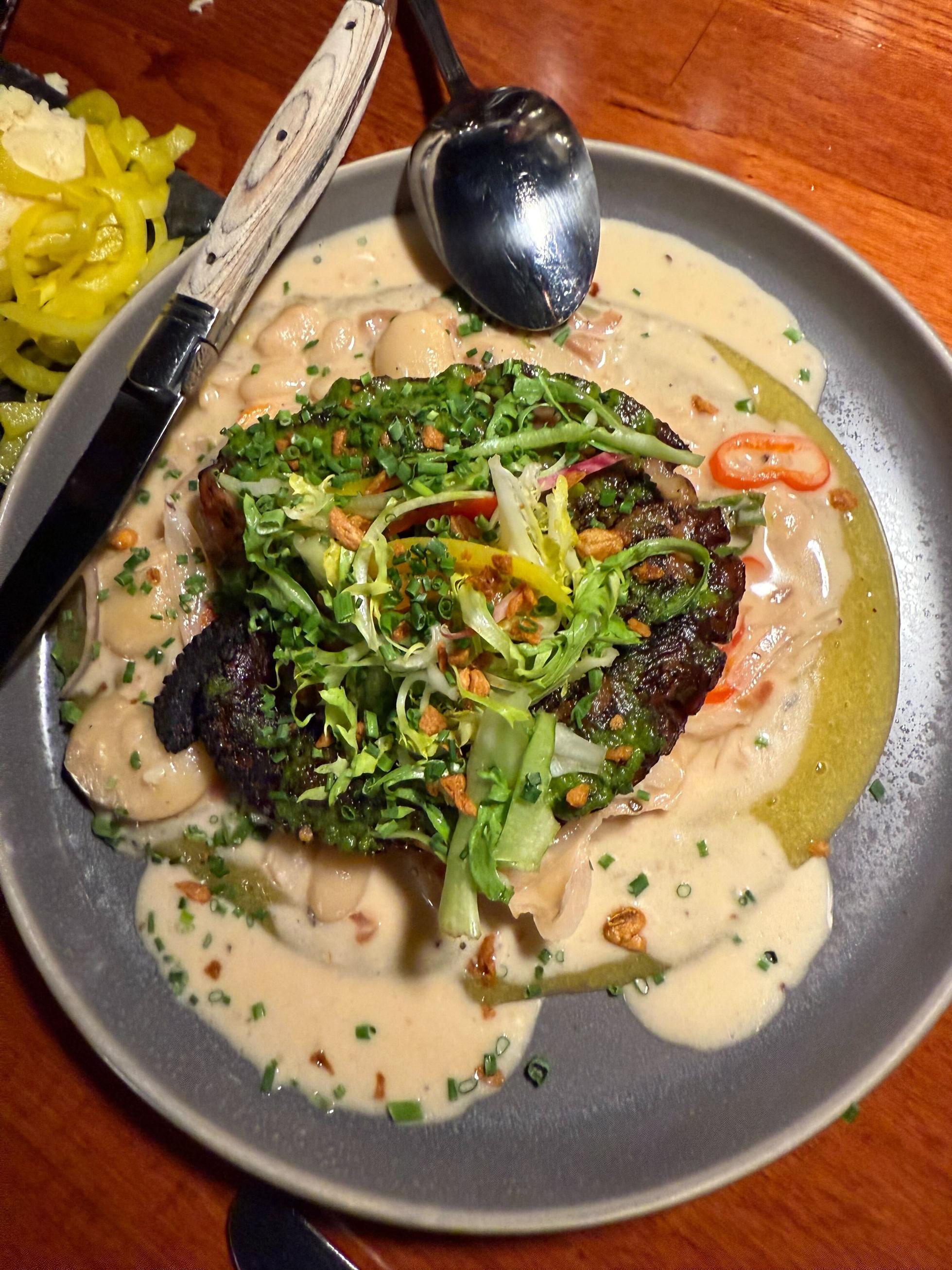 A plate of crispy octopus atop creamy white beans from Le Coin in Seattle.