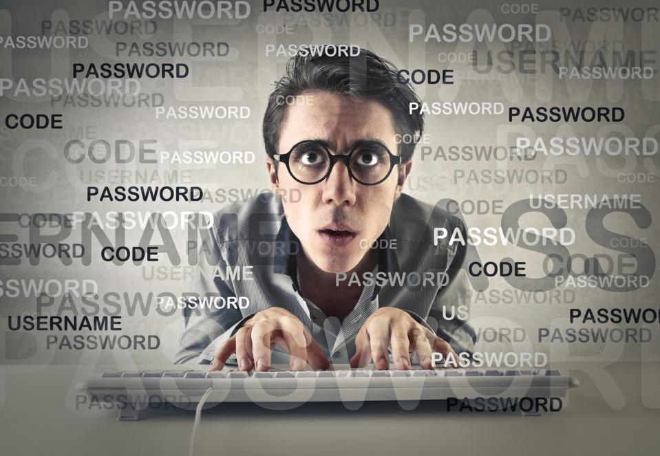 A man in glasses at keyboard, password and code wordcloud surrounding